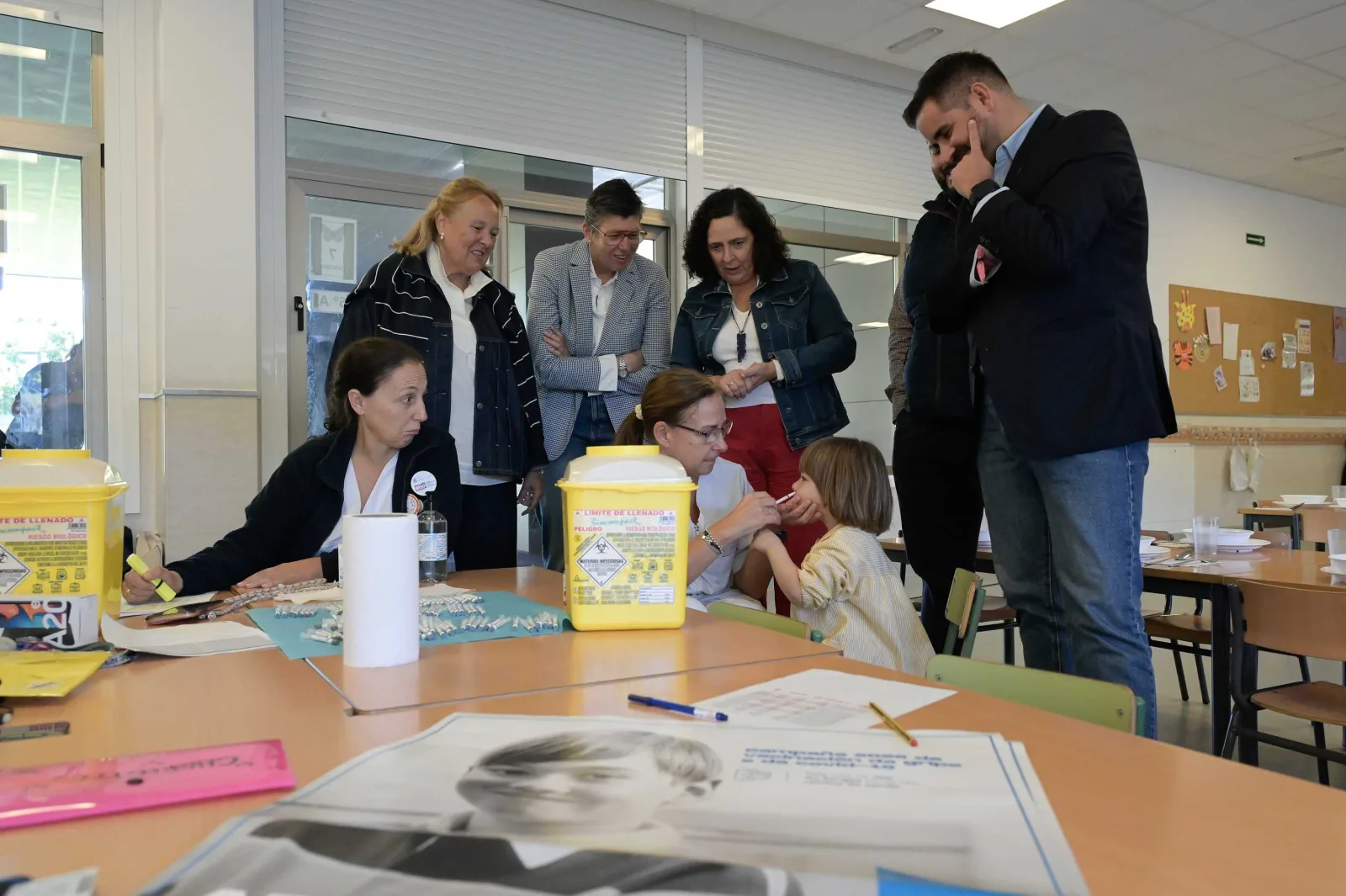 Unha enfermeira aplica pola nariz a vacina da gripe a un alumno de infantil do CEIP Vales Villamarín, mentres as autoridades da visita observan.