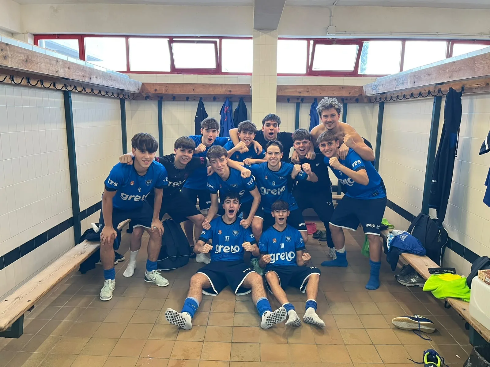 Los jugadores del juvenil del Troula Betanzos Grelo, de azul, celebran la victoria en el vestuario del pabellón.