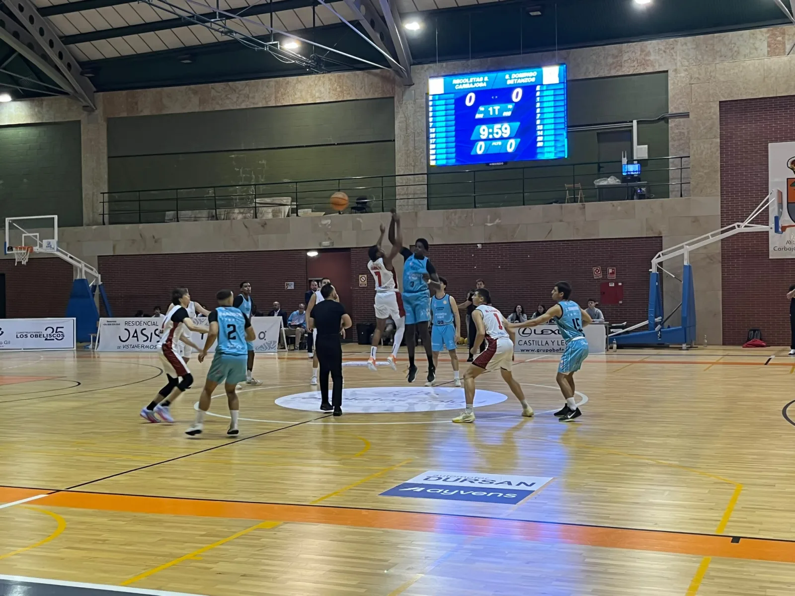 Salto inicial do partido entre o Recoletas Salud, de azul celeste, e o Ineltrón Santo Domingo, de branco e vermello, no pavillón de Carbajosa de La Sagrada co marcador a cero.
